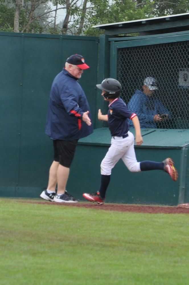 Coach Rick giving a high five to a player rounding third base