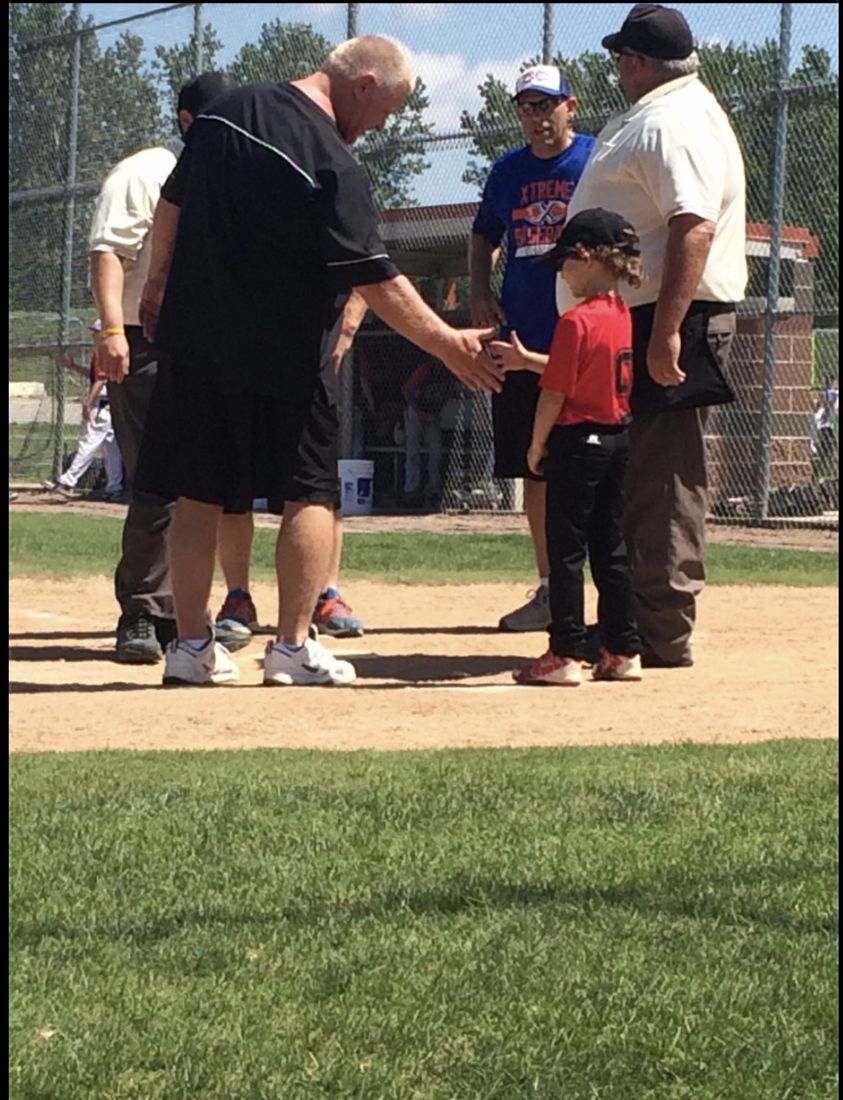 Coach Rick shaking hands with a young player at home plate